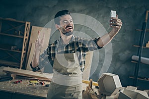 Positive success hardwood furniture restoration entrepreneur workman make selfie on smartphone show v-sign enjoy his
