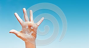 Positive symbol drawing by sunscreen sun cream, suntan lotion on caucasian open hand on blue sky background.