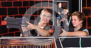 positive teen boy having fun on laser tag arena with his older sister
