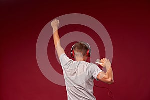 Positive teen guy in headphones shows listening to music in headphones. Behind