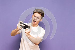Positive teenage gamer in a white T-shirt plays a game on a smar