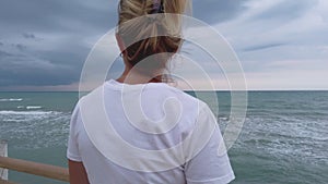 Positive thinking concept - single woman staring at stormy and windy sea smiling alone
