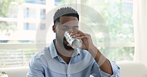 Positive thirsty handsome young African man drinking fresh clear water