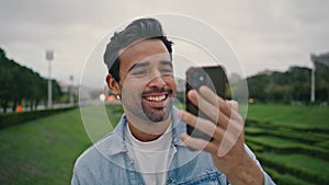 Positive tourist video calling by mobile phone spending weekend in park close up