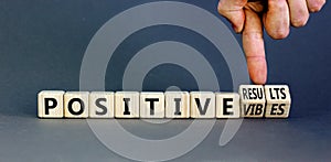 Positive vibes results symbol. Concept words Positive vibes or Positive results on cubes. Businessman hand. Beautiful grey table