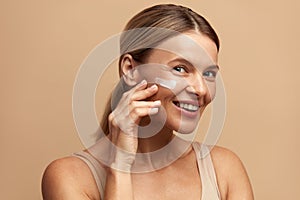 Positive Woman Applying Face Cream. Female With Fresh Skin Applying Cosmetic