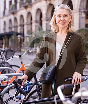 Positive woman with bike on spring city street