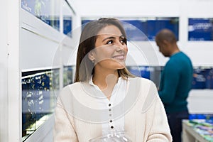 Positive woman choosing aquarium fish in shop