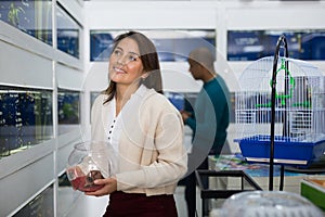 Positive woman choosing aquarium fish in shop