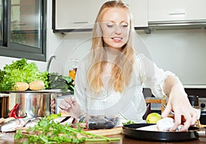 Positive woman cooking fish in flour photo