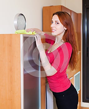 Positive woman dusting wooden furiture