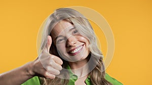 Positive woman with hand sign like, thumbs up gesture. Lady on yellow background