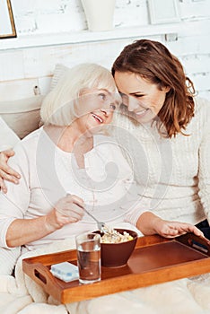 Positive woman and her smiling beautiful granddaughter embracing