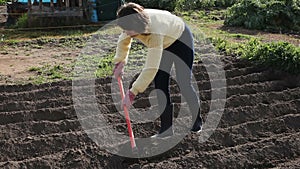 Positive woman hoeing off weeds in domestic garden