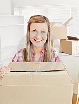 Positive woman holding a box in her new house