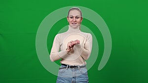 Positive woman imitating virtual cosmetics testing on green screen. Slim beautiful Caucasian lady smelling invisible