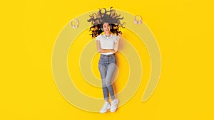 Positive Woman Listening Music Pointing Finger Choosing Headphones, Yellow Background