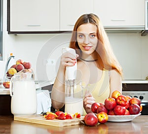 Positive woman making beverages with nectarines and milk