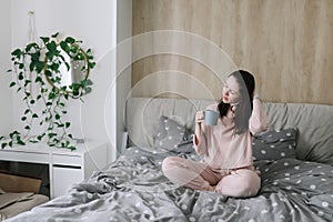 Positive woman with pillow sitting in bed at home. Sweet dreams and good morning concept