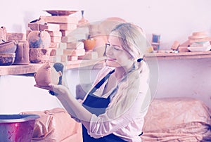 Positive woman potter carrying ceramic vessels