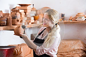 Positive woman potter carrying ceramic vessels