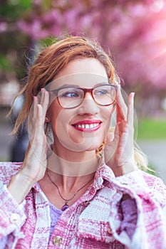 Positive woman put on eyeglasses to see clearly outdoors