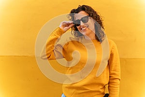 Positive woman in sunglasses near wall