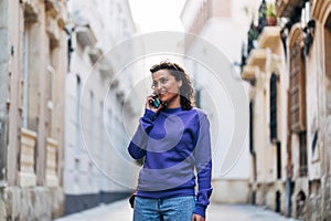 Positive woman talking on smartphone in city