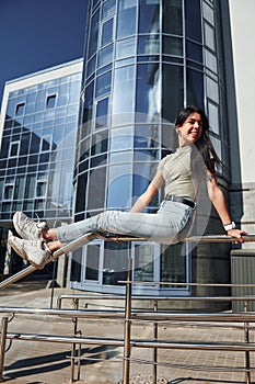 Positive woman with tattoo on arm have fun outdoors against business building at sunny daytime