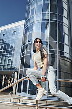 Positive woman with tattoo on arm have fun outdoors against business building at sunny daytime