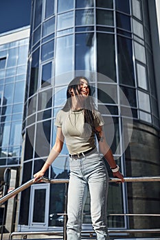 Positive woman with tattoo on arm have fun outdoors against business building at sunny daytime