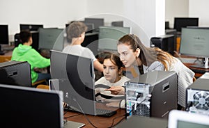 Positive woman teacher together with the girl teaches how to work on computer