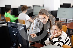 Positive woman teacher together with the girl teaches how to work on computer