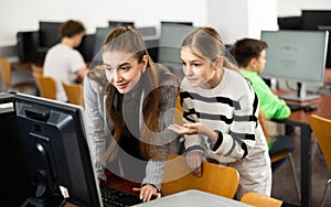 Positive woman teacher together with the girl teaches how to work on computer