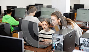 Positive woman teacher together with the girl teaches how to work on computer