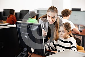 Positive woman teacher together with the girl teaches how to work on computer