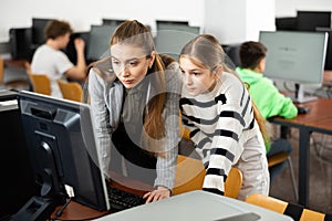 Positive woman teacher together with the girl teaches how to work on computer