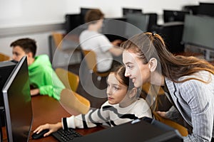 Positive woman teacher together with the girl teaches how to work on computer