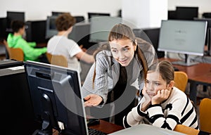 Positive woman teacher together with the girl teaches how to work on computer