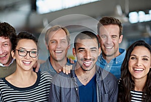 Positive work environment. a smiling group of coworkers standing in an office.