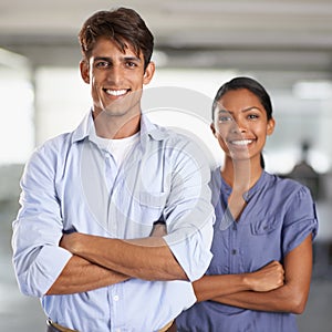 Positive work environment. A young business team standing with arms folded.