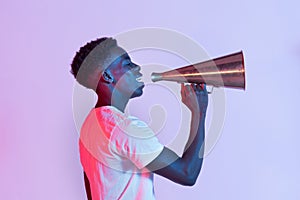 Positive young African American man with vintage megaphone in studio