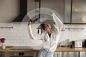 Positive young african female dancing at kitchen in good mood