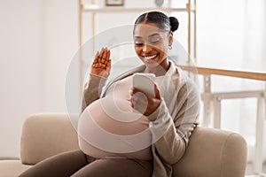 Positive young black pregnant woman have video call on phone