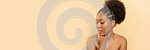Positive young black woman with bare shoulders and beautiful skin on a beige background. Web banner