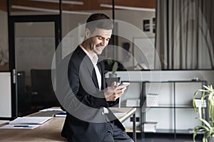 Positive young business professional man reading text on cellphone