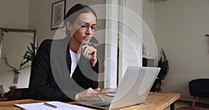 Positive young business professional woman in glasses thinking at workplace