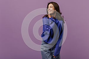 Positive young caucasian girl laughing looking away on purple background with space for text.