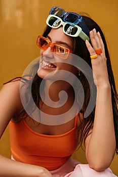 Positive young caucasian girl in three pair of sunglasses looking at distance and smiling.