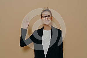 Positive young caucasian woman in classic wear isolated on beige background showing ok sign